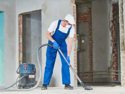 service man cleaning and removing construction dust with vacuum cleaner after repair